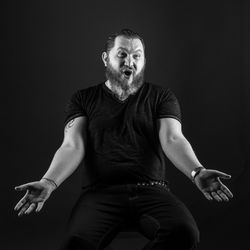 Man looking away while sitting against black background