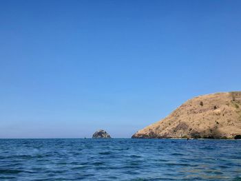 Scenic view of sea and island against clear blue sky