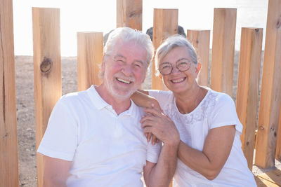 Portrait of smiling couple standing against wooden wall