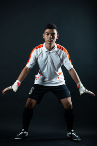 Portrait of young man standing against black background