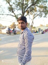 Portrait of young man standing on road in city