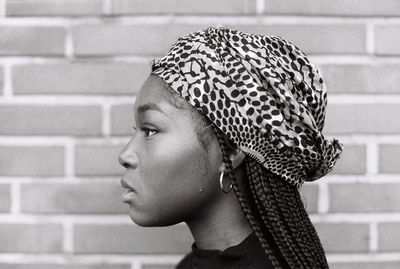 Side view of woman against brick wall