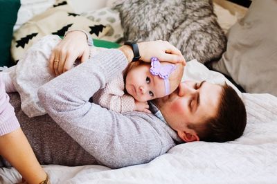 Father kissing daughter lying on bed at home