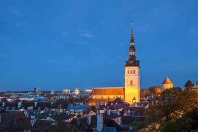 High angle view of illuminated city against blue sky