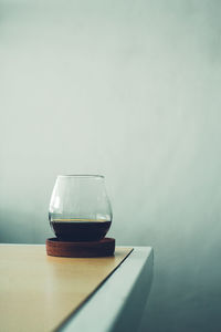 Close-up of empty glass on table against wall