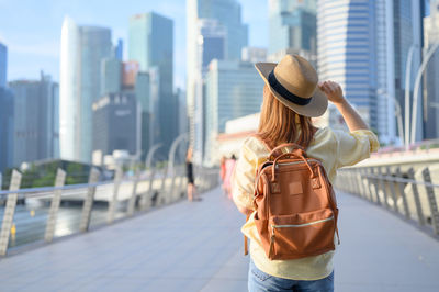 Rear view of woman wearing hat standing in city