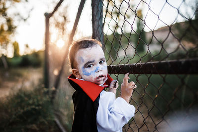 Portrait of boy standing by fence