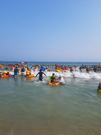 People on sea against clear sky