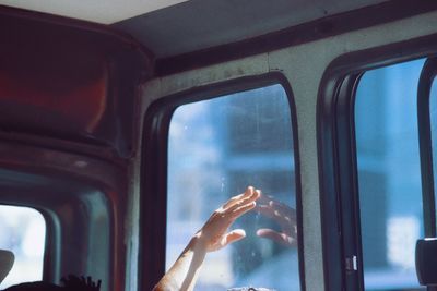 Cropped hand of person by window in bus