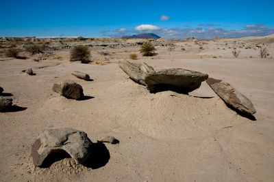 Rocks on sand against sky