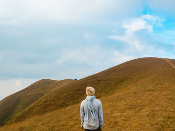 Rear view of woman standing on land against sky