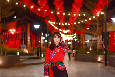 Portrait of smiling young woman in illuminated traditional clothing