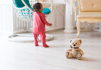 Rear view of girl playing with toy on floor