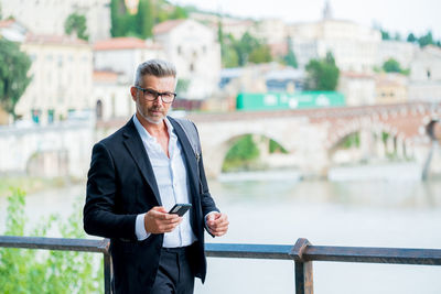 Businessman holding mobile phone while standing outdoors