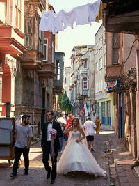 Rear view of people walking on street amidst buildings in city