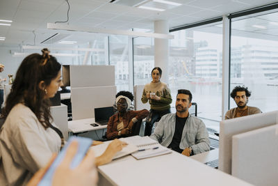 Multiracial colleagues listening to businesswoman discussing strategy at office