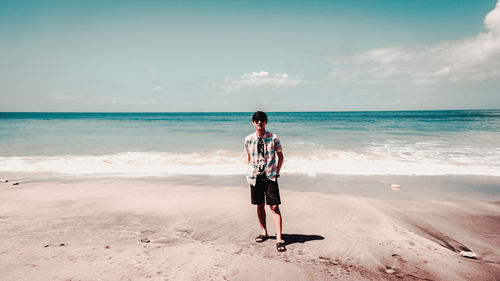 Full length of man standing on beach against sky