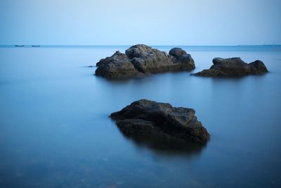 Rock formation in sea against clear sky