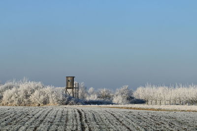 Snow covered field against clear blue sky