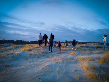 People walking on shore against sky