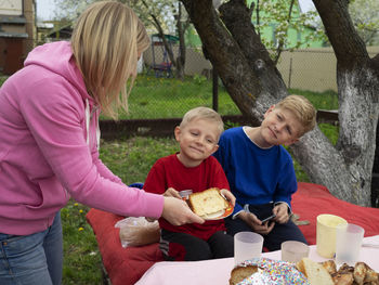 Woman serving bread to sons at lawn