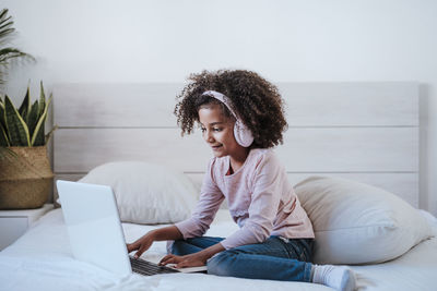 Young woman using phone while sitting on sofa at home