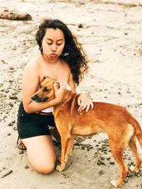 Young woman embracing with dog at beach