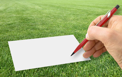 Cropped image of person holding paper against wall