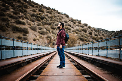 Rear view of man standing on railroad track