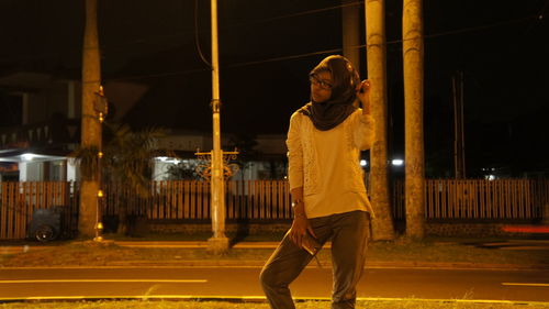 Young woman in hijab standing on road at night