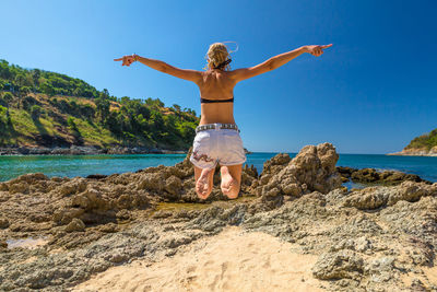 Woman jumping at beach against sky