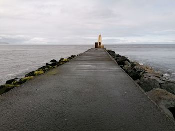 Surface level of walkway by sea against sky