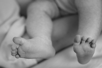 Low section of baby sleeping on bed 