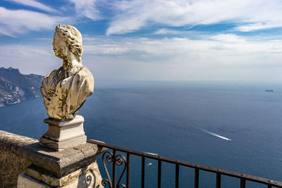 Statue by sea against sky