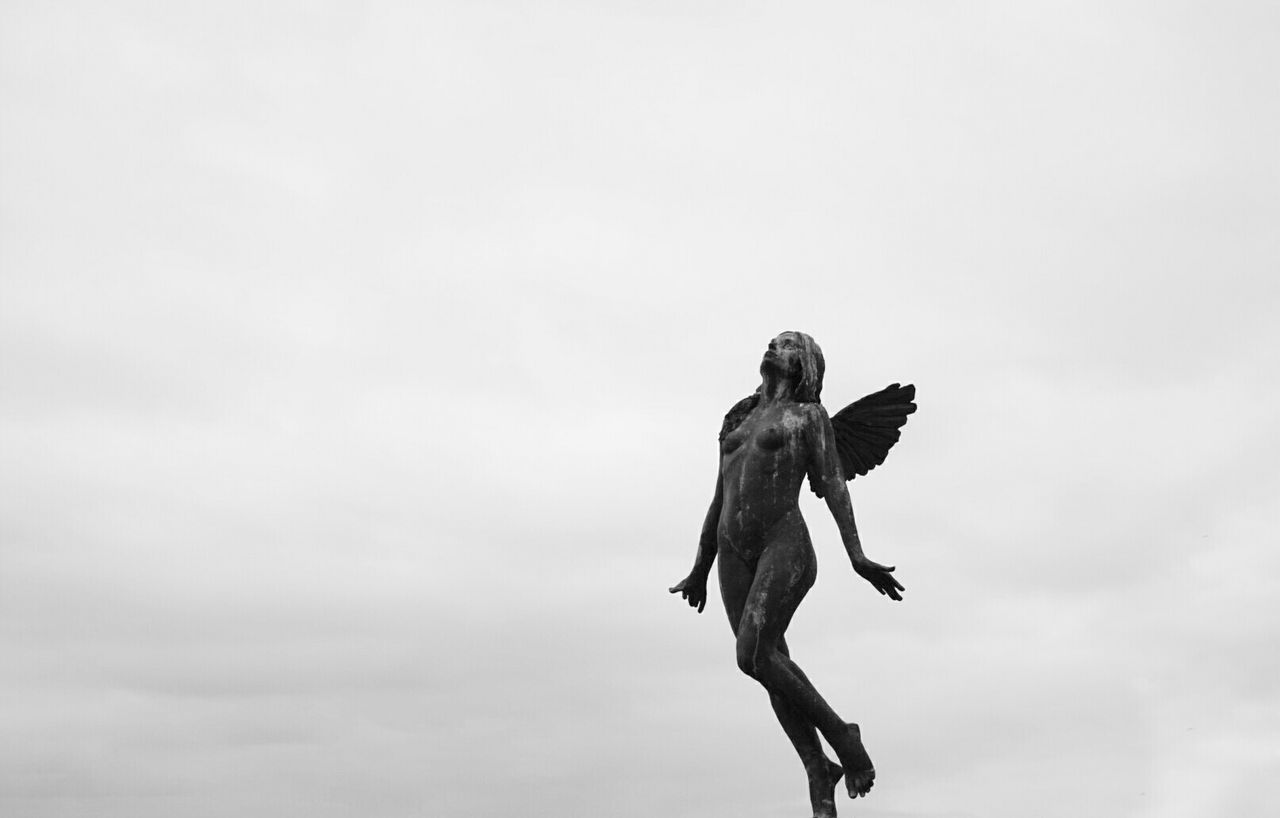 low angle view, sky, full length, statue, human representation, sculpture, cloud - sky, copy space, men, outdoors, day, mid-air, leisure activity, cloud, nature, art and craft, bird