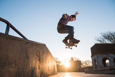 Low angle view of man skateboarding against clear sky