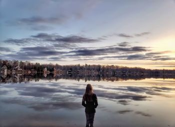 Woman standing on snow covered landscape during sunset