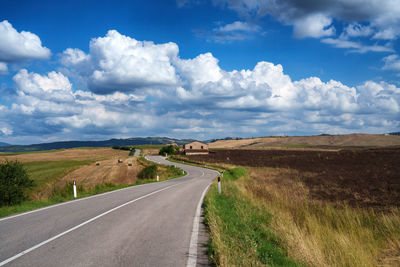 Road amidst field against sky