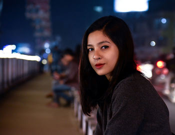 Portrait of young woman in city at night