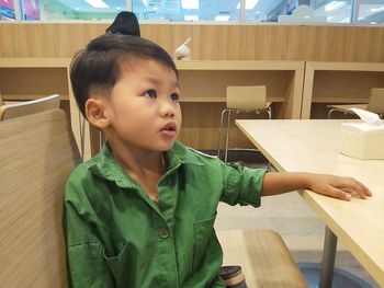 Cute boy looking away while sitting on table