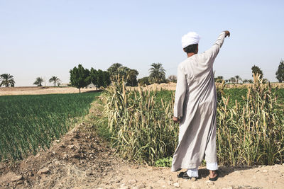 Rear view of man standing on field against clear sky