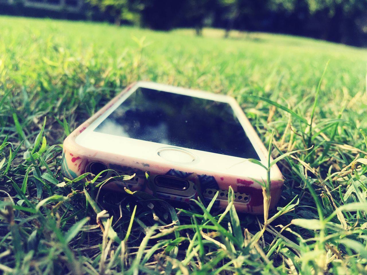 CLOSE-UP OF SMART PHONE IN GRASS FIELD