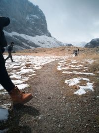 Woman standing on snow covered mountain against sky