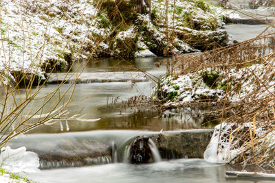 Scenic view of river flowing by trees during winter