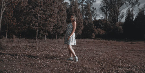 Portrait of woman standing on field against trees