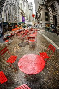 Red and chairs on sidewalk cafe by street in city