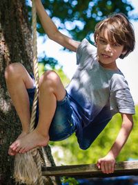 Low angle view of boy sitting on tree