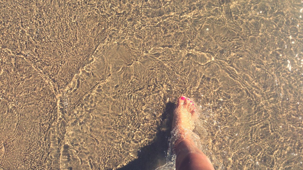 low section, person, lifestyles, personal perspective, leisure activity, barefoot, water, human foot, sand, beach, high angle view, standing, unrecognizable person, sunlight, wet, part of