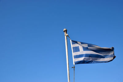 Low angle view of flag against clear blue sky