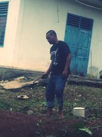 Full length of young man standing in yard against building